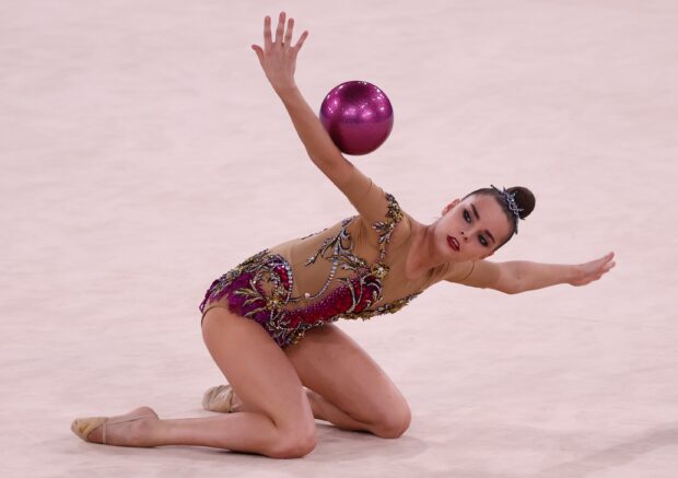 A rhythmic gymnast performs a balanced pose while holding a sparkling ball during a routine, 2K Desktop Wallpaper