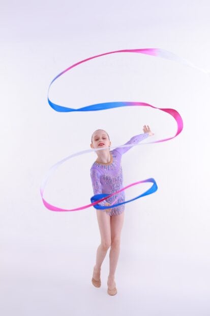 A rhythmic gymnast performs a ribbon routine with fluid movements, 2K Phone Wallpaper