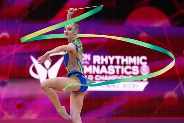A rhythmic gymnastics athlete performs with a colorful ribbon during a competition, HD Desktop Wallpaper