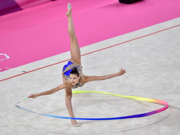 A rhythmic gymnast performs a skillful routine with a vibrant ribbon on the floor, HD Desktop Wallpaper