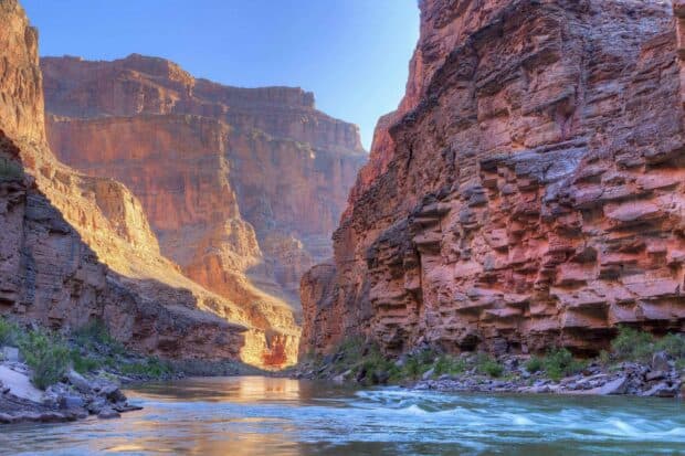 The Grand Canyon features a flowing river surrounded by towering rock cliffs under a clear sky, HD Desktop Wallpaper