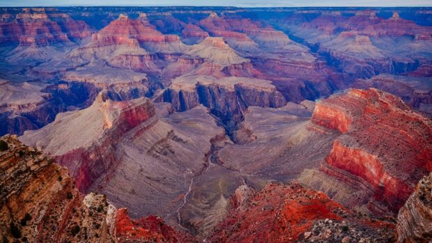 The Grand Canyon showcases layered red rock formations under a blue sky, 4K Desktop Wallpaper