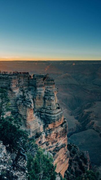 A breathtaking view of the Grand Canyon with visitors admiring the sunset on the cliffs, HD Phone Wallpaper