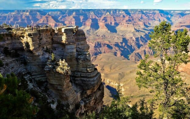Tourists observe the vast Grand Canyon landscape under a clear sky, 2K Desktop Wallpaper