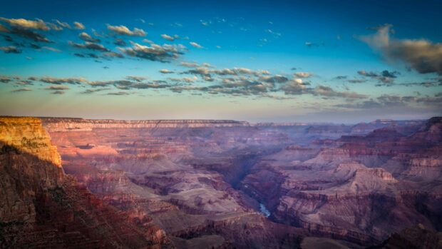 The Grand Canyon displays stunning colors under a clear sky at sunset, 4K Desktop Wallpaper