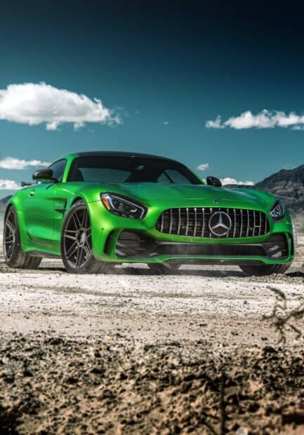 A green Mercedes Benz Amg Gt is driving on a dusty desert road under a clear blue sky, HD Phone Wallpaper