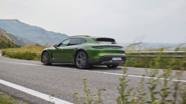 A green Porsche Taycan is driving along a winding road in a mountainous area with blurred background scenery, 4K Desktop Wallpaper