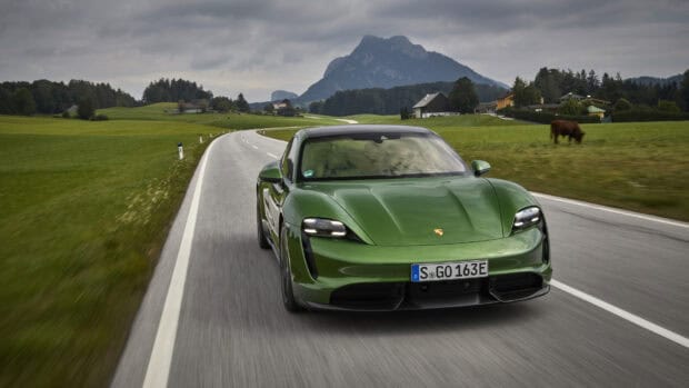 A green Porsche Taycan is driving on a winding road with mountains and fields in the background, HD Desktop Wallpaper