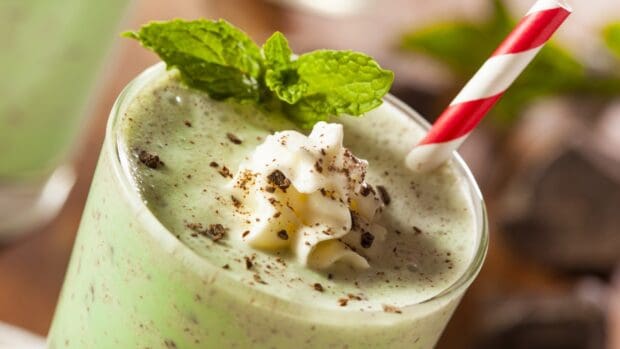 A close up of a green mint milkshake topped with whipped cream and chocolate flakes with a red and white straw, HD Desktop Wallpaper