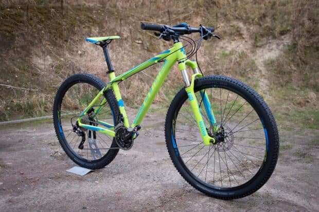 A green Cube bike stands ready on a rugged trail with nature backdrop, HD Desktop Wallpaper