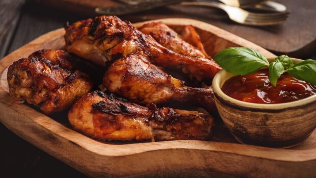 A plate of grilled chicken drumsticks is served with dipping sauce and fresh herbs, 4K Desktop Wallpaper