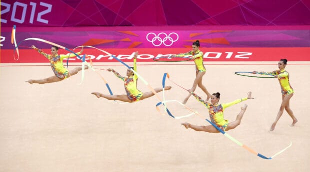 A group of rhythmic gymnasts perform with ribbons and hoops in a competition, 2K Desktop Wallpaper