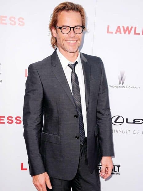 Guy Pearce is smiling while wearing a dark suit and glasses at an event, 2K Desktop Wallpaper