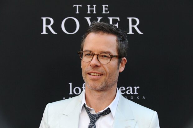 Guy Pearce in a light suit and glasses smiling at an event, 2K Desktop Wallpaper