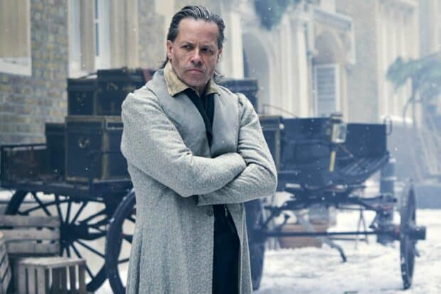 Guy Pearce stands with arms crossed in a snowy old city setting, HD Desktop Wallpaper