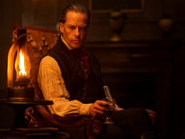 Guy Pearce is sitting in a dimly lit room holding a glass with a serious expression, HD Desktop Wallpaper