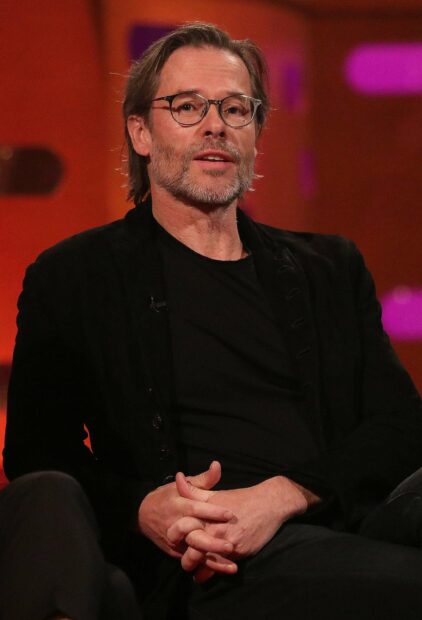 Guy Pearce wallpapers showing him seated wearing glasses and a black jacket, 2K Phone Wallpaper
