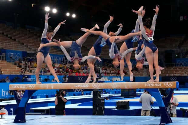 A gymnast demonstrates a complex routine on the balance beam during a competition, HD Desktop Wallpaper
