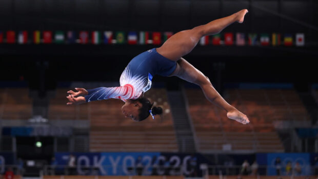 A gymnast is captured in mid air during a balance beam routine at the Tokyo Olympics, 2K Desktop Wallpaper