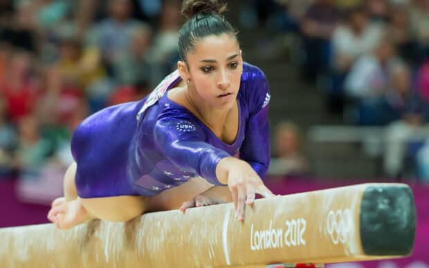 A gymnast is focused while performing on the balance beam at a competition, 2K Desktop Wallpaper