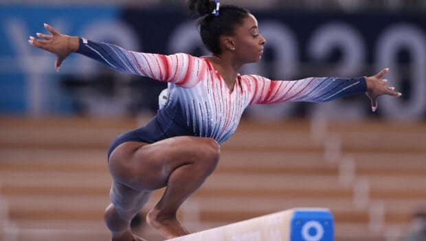 A gymnast concentrates while performing on a balance beam during competition, 2K Desktop Wallpaper