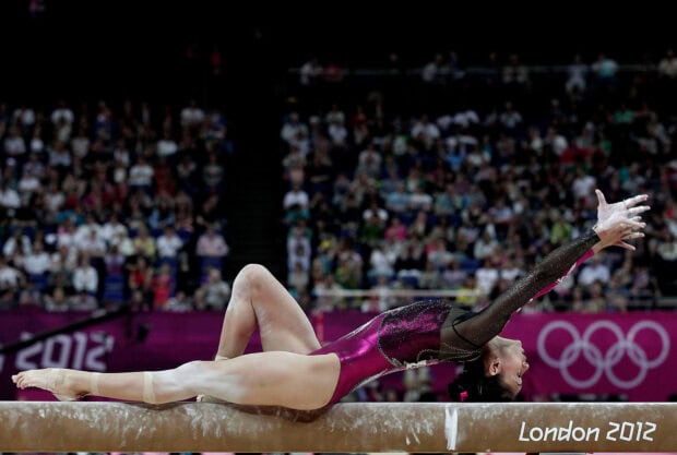 A gymnast stretches backward on a balance beam during a competition, HD Desktop Wallpaper