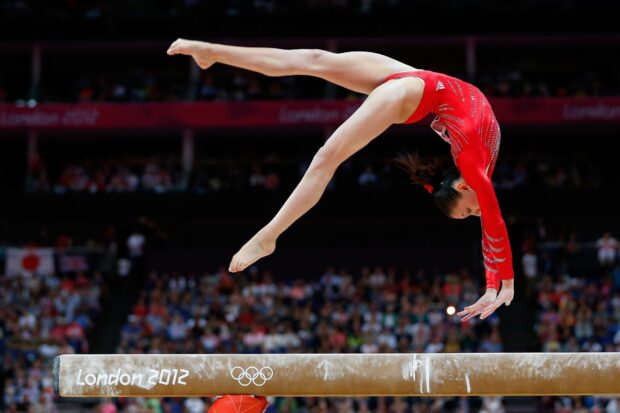 A gymnast is captured mid air while performing on the balance beam at the London 2012 Olympics, HD Desktop Wallpaper