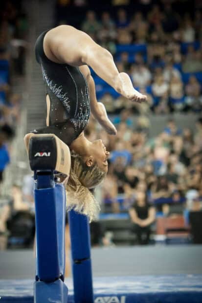 A gymnast executes a skill on the balance beam during competition, HD Phone Wallpaper
