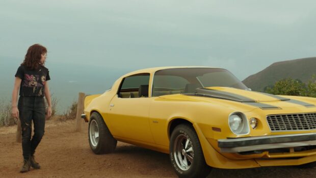 Hailee Steinfeld is standing beside a vintage yellow car with a scenic background, HD Desktop Wallpaper