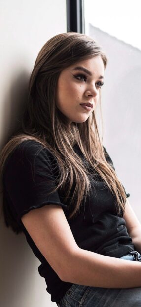 Hailee Steinfeld is sitting by a window looking outside in a thoughtful pose, HD Phone Wallpaper