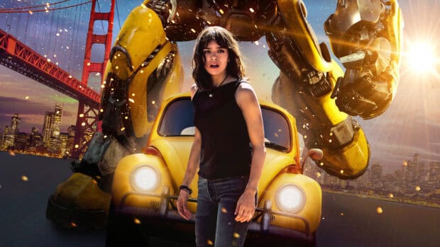 Hailee Steinfeld stands in front of a yellow robot and car near a city bridge at sunset, HD Desktop Wallpaper