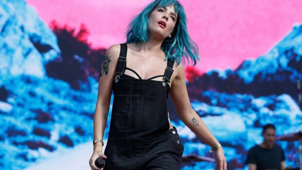 A photo of Halsey with bright blue hair performing on stage with colorful background for Halsey Wallpapers