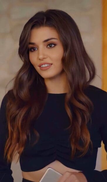 A portrait of Hande Ercel with flowing hair and a soft smile holding a phone, HD Phone Wallpaper