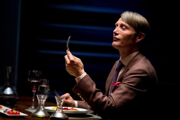 A man savoring food with eyes closed at a dinner table with wine and dishes, 2K Desktop Wallpaper