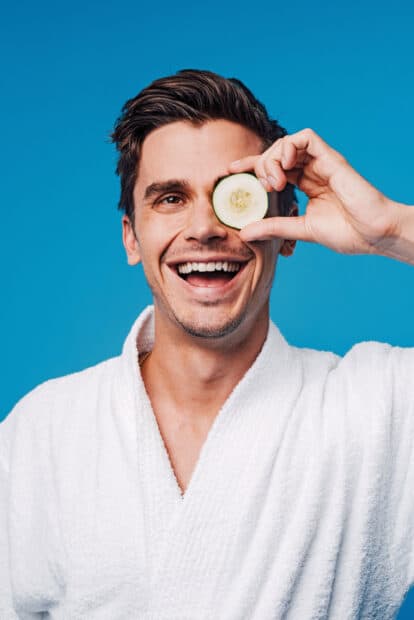 A man in a white robe smiles while holding a cucumber slice over one eye, 2K Mobile Wallpaper