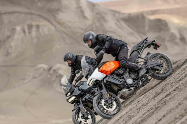 Two riders on Harley Davidson Pan America 1250 motorcycles climbing a steep sandy hill, HD Desktop Wallpaper