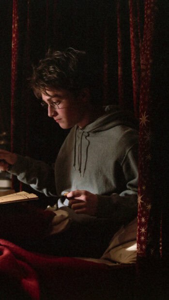 Harry Potter is reading a book in a dimly lit room with red curtains, HD Phone Wallpaper
