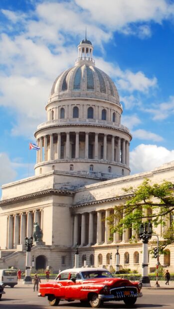 A classic red car drives past the historic Capitol building under a bright blue sky in Havana Cuba, HD Mobile Wallpaper