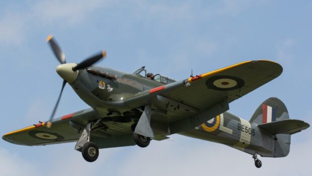 A hawker hurricane aircraft flying against a blue sky with visible pilot and propeller, HD Desktop Wallpaper
