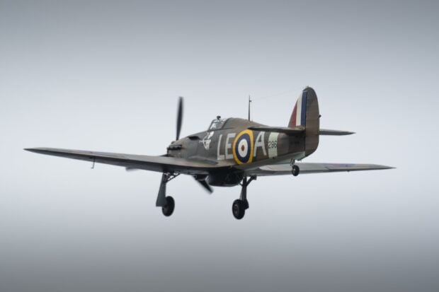 A Hawker Hurricane aircraft flies with landing gear extended against a clear sky, HD Desktop Wallpaper