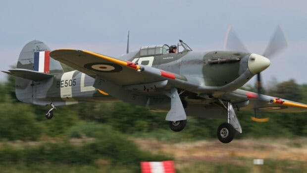 A Hawker Hurricane is captured flying low over the countryside with visible pilot and propeller motion, HD Desktop Wallpaper