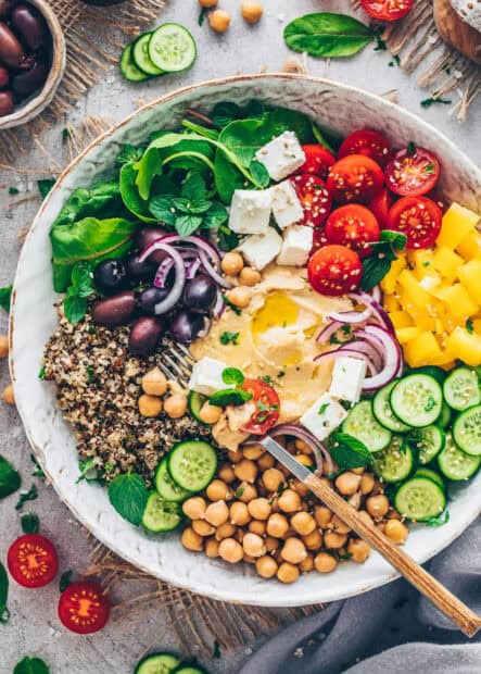A vibrant quinoa bowl with cherry tomatoes, cucumbers, and chickpeas on a table, HD Mobile Wallpaper