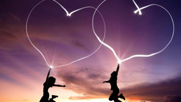 Two figures creating heart shape with light trails during sunset, 4K Desktop Wallpaper