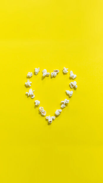 White popcorn forming a heart shape on a bright yellow background, 4K Mobile Wallpaper