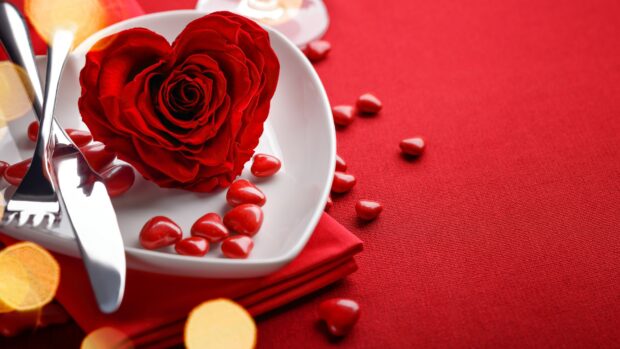 A heart shape rose and small candy hearts are placed on a plate with cutlery on a red cloth, 4K Desktop Wallpaper