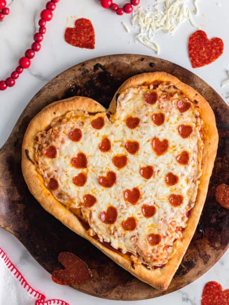 A heart shaped pizza topped with cheese and pepperoni slices on a baking tray, 2K Desktop Wallpaper
