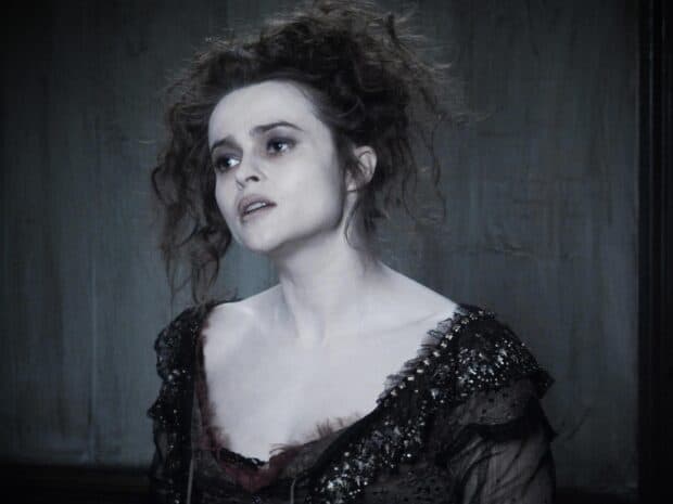 Helena Bonham Carter wears a dark intricate dress with tousled hair in a dim setting, HD Desktop Wallpaper
