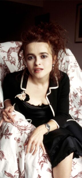 Helena Bonham Carter wears a black outfit sitting on a floral chair, 2K Mobile Wallpaper