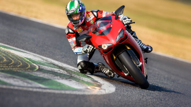 A racer is leaning into a sharp turn on a race track with intense focus, HD Desktop Wallpaper