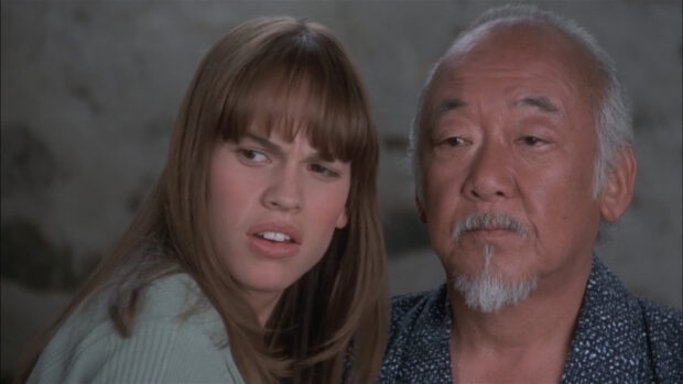 Hilary Swank and a white bearded man sharing an intense moment in a scene, HD Desktop Wallpaper